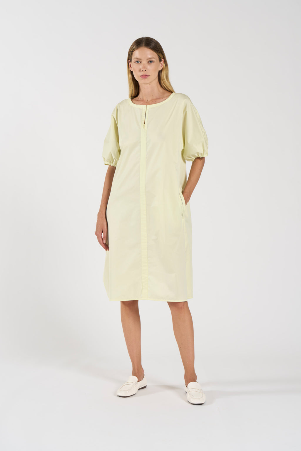 Abito in popeline di cotone con maniche a sbuffo. Look minimalista, taglio moderno, la cerniera davanti termina nel girocollo; cucitura centrale.